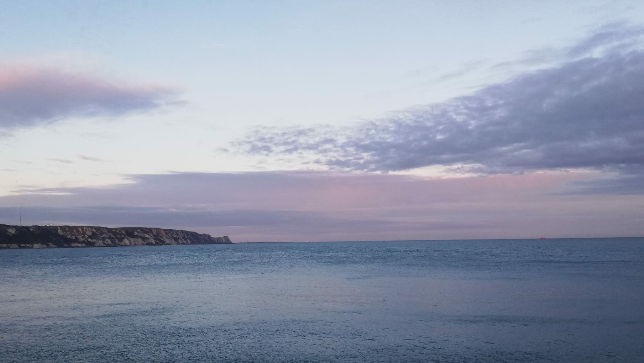 calm sea horizon at sunset with soft sky, creating a sense of peace and gentle wellbeing